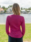 Woman wearing a pink long-sleeve shirt by a body of water.