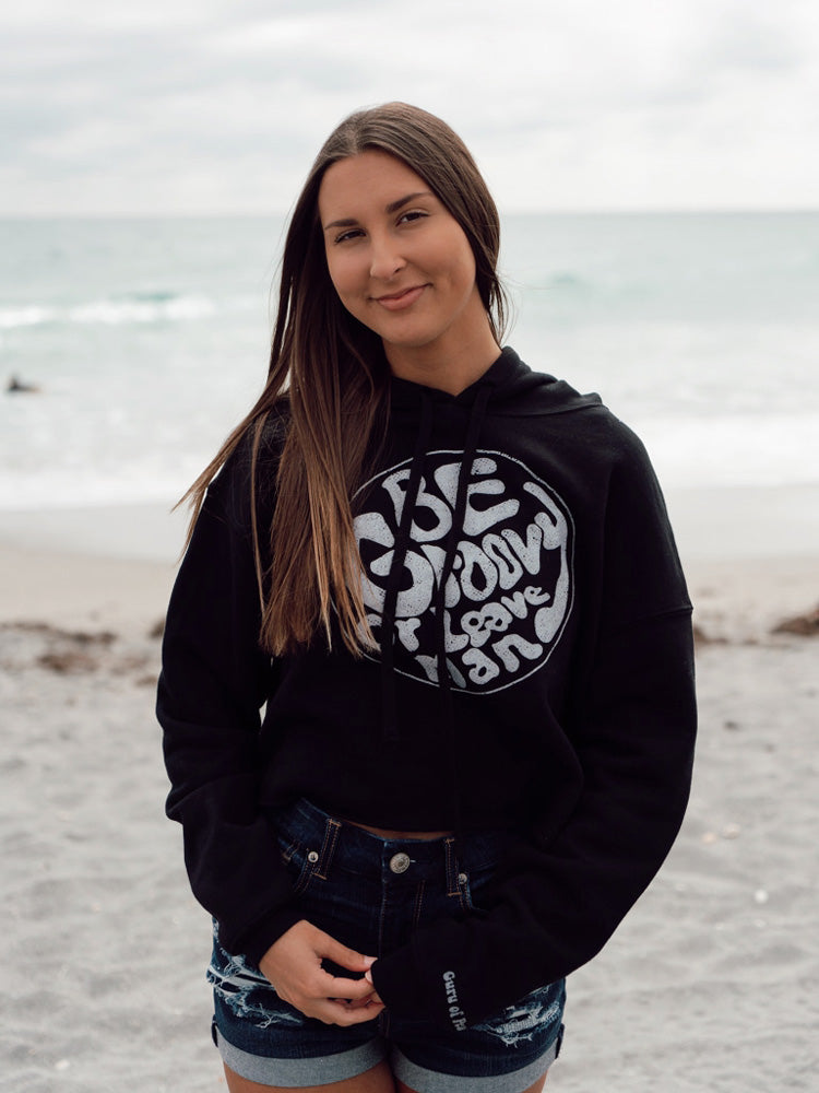 Woman wearing a black hoodie with white text on a beach