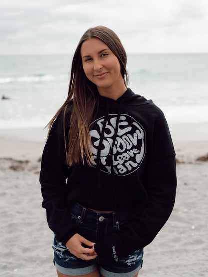 Woman wearing a black hoodie with white text on a beach