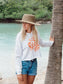 Woman wearing a white hoodie with orange text on a beach