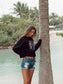 Woman wearing a black hoodie with white text on a beach