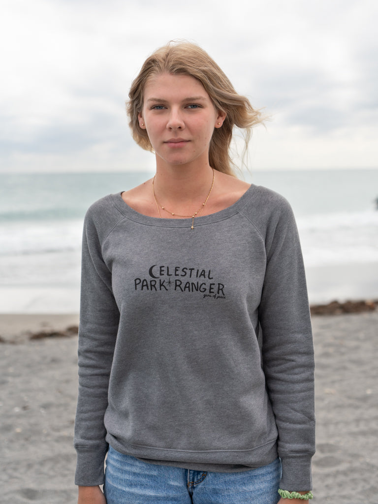 Woman wearing a gray 'Celestial Park Ranger' shirt with an ocean background