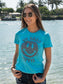 Woman wearing a turquoise t-shirt with smiley face design with water in the background