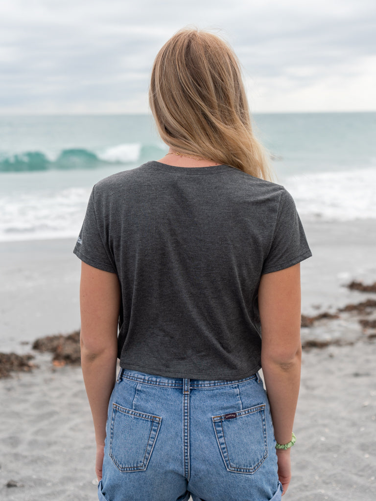 Woman wearing a dark gray t-shirt with a peace symbol on a beach