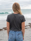 Woman wearing a dark gray t-shirt with a peace symbol on a beach