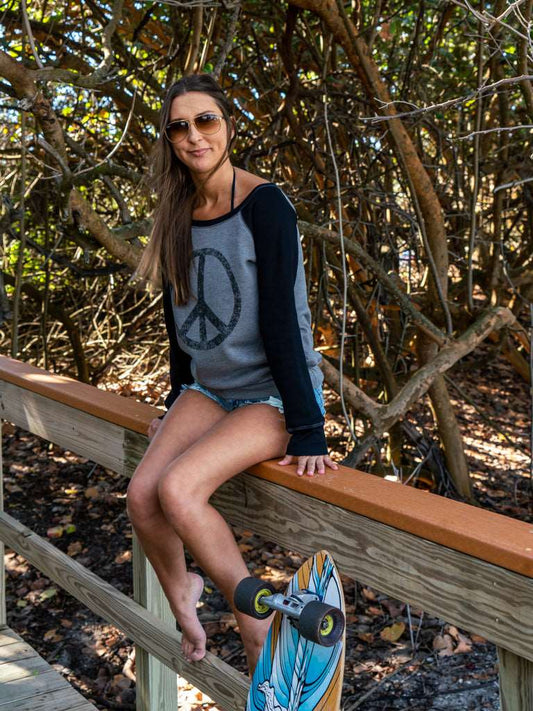 Woman sitting on a wooden railing with a skateboard, surrounded by trees