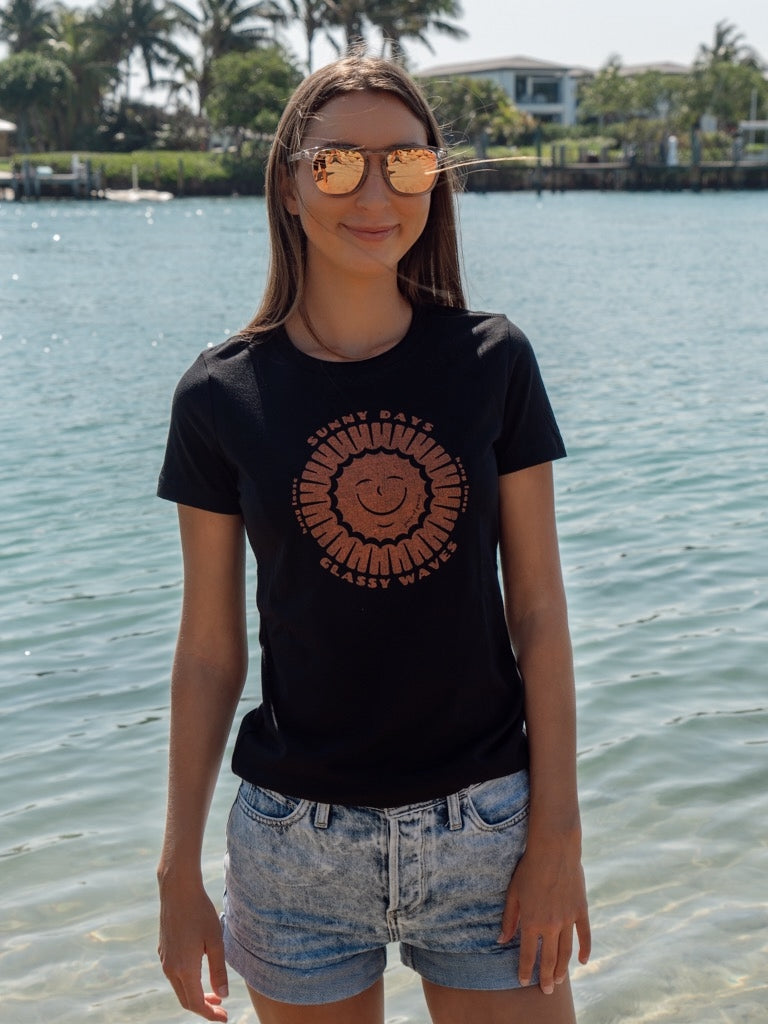 Person wearing a black t-shirt with a smiley face design by the water
