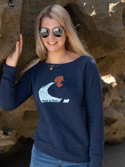 Woman wearing a navy blue sweatshirt with a graphic design, standing against a rocky background.