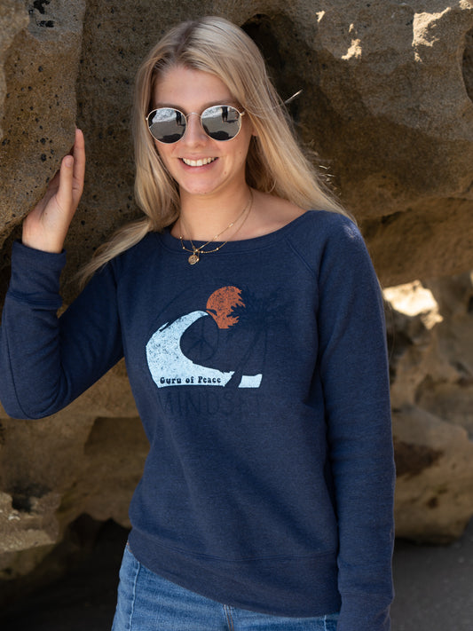 Woman wearing a navy blue sweatshirt with a graphic design, standing against a rocky background.