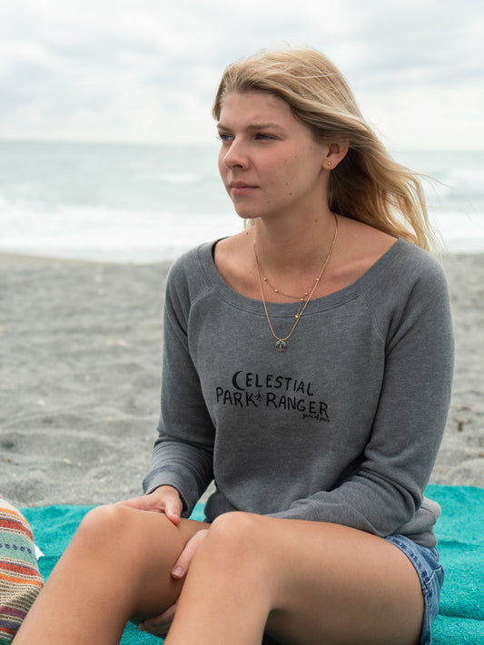 Woman wearing a gray 'Celestial Park Ranger' shirt with an ocean background
