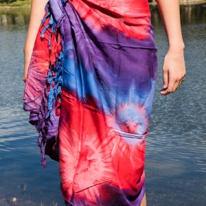 A person standing by water wearing a blue sarong styled as a skirt.