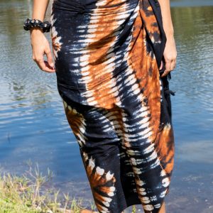 A person standing by water wearing a blue sarong styled as a skirt.
