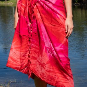 A person standing by water wearing a blue sarong styled as a skirt.