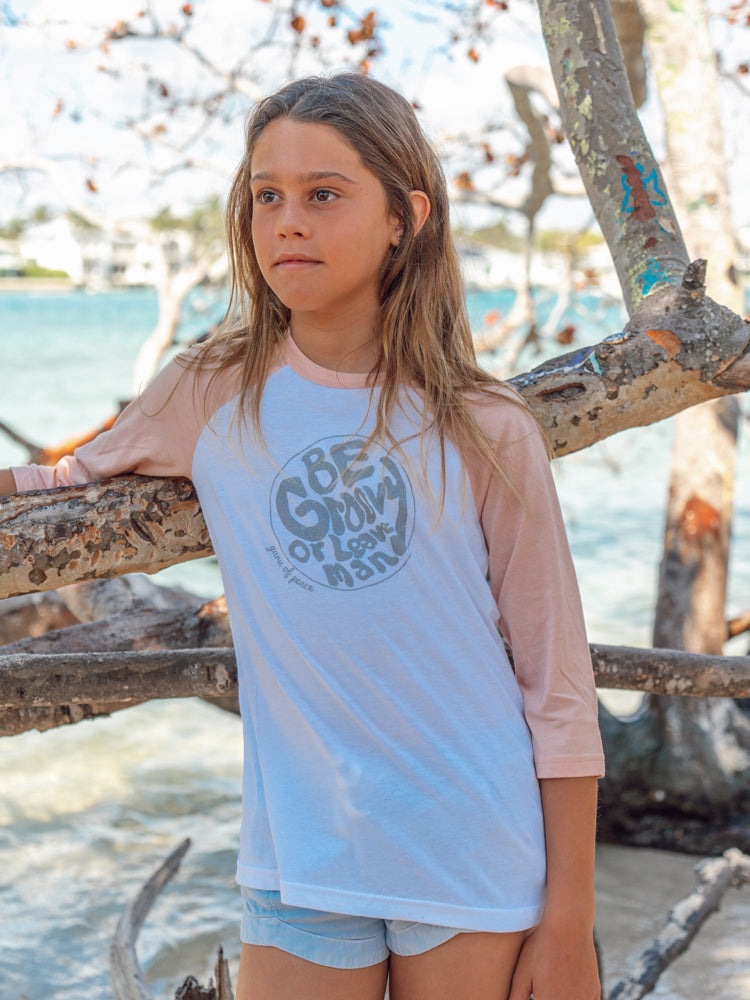 Young girl wearing a 'Be Groovy' shirt by the ocean