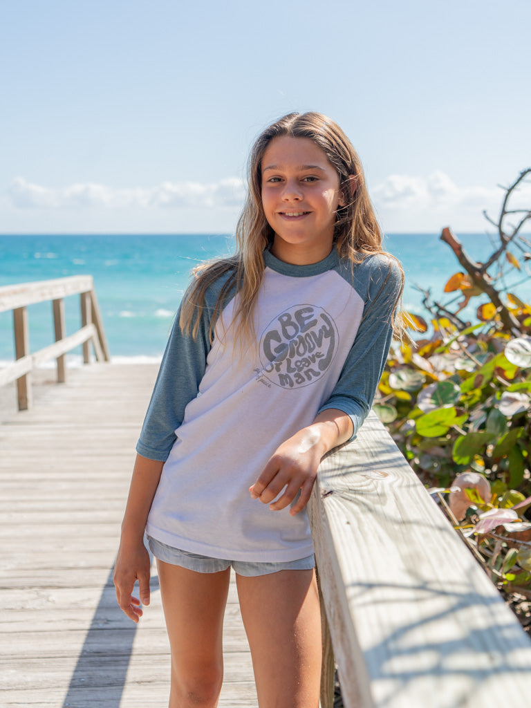 Young girl wearing a 'Be Groovy' shirt by the ocean