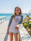 Young girl wearing a 'Be Groovy' shirt by the ocean