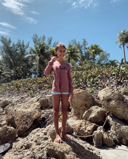 Person standing on rocks with palm trees and blue sky in the background