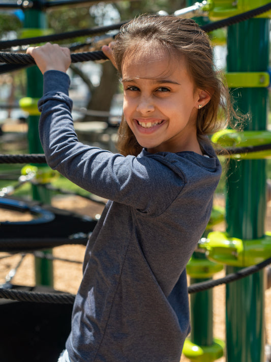 Young girl wearing a grey long sleeve shirt  playing on a playground