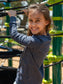 Young girl wearing a grey long sleeve shirt  playing on a playground