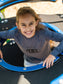 Young girl wearing a grey long sleeve shirt with the words 'Guru of Peace' playing on a playground