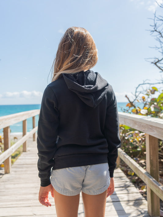 Young girl wearing black hoodie on a beach