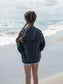 Young girl wearing grey hoodie standing on a beach