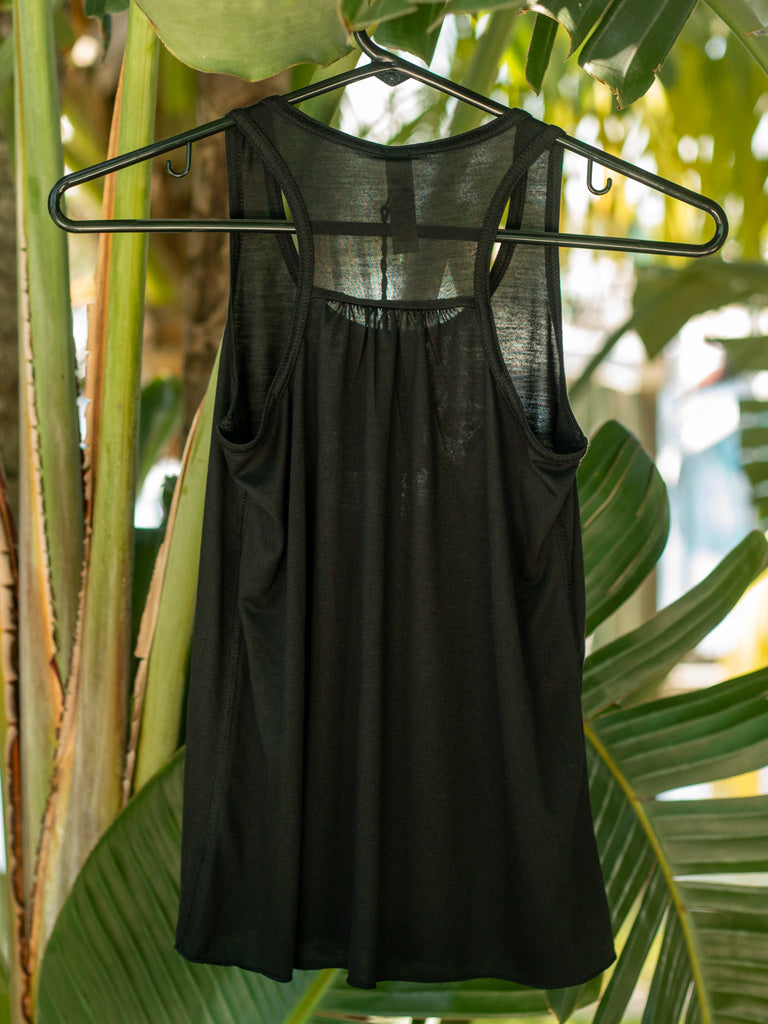 Black tank top on a hanger against a leafy green background.