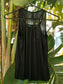 Black tank top on a hanger against a leafy green background.
