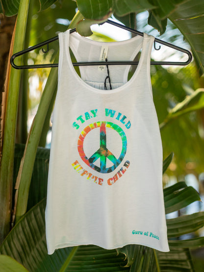 White tank top with colorful peace sign and text 'Stay Wild, Explore Child' on a hanger against a leafy green background.