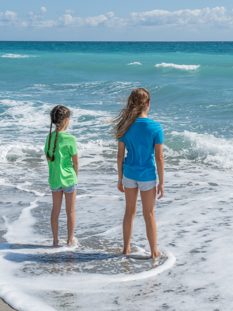 Two girls standing on a beach in the ocean waves