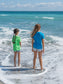 Two girls standing on a beach in the ocean waves